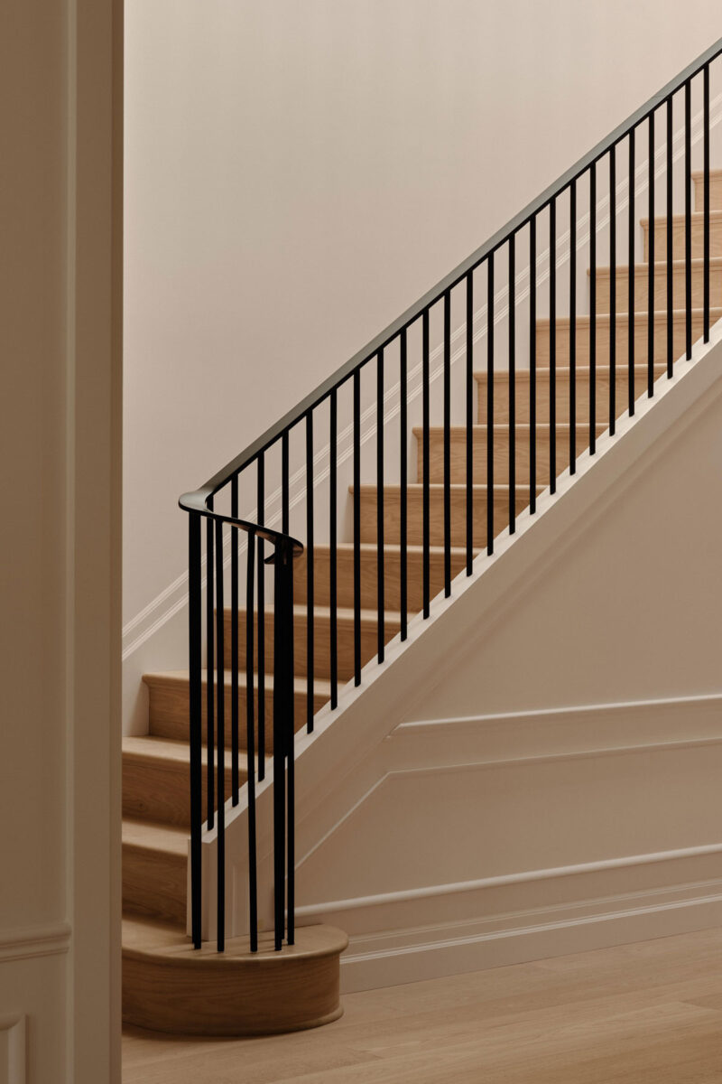 Contemporary staircase detail with recessed black steel handrail and traditional molding in Montreal home
