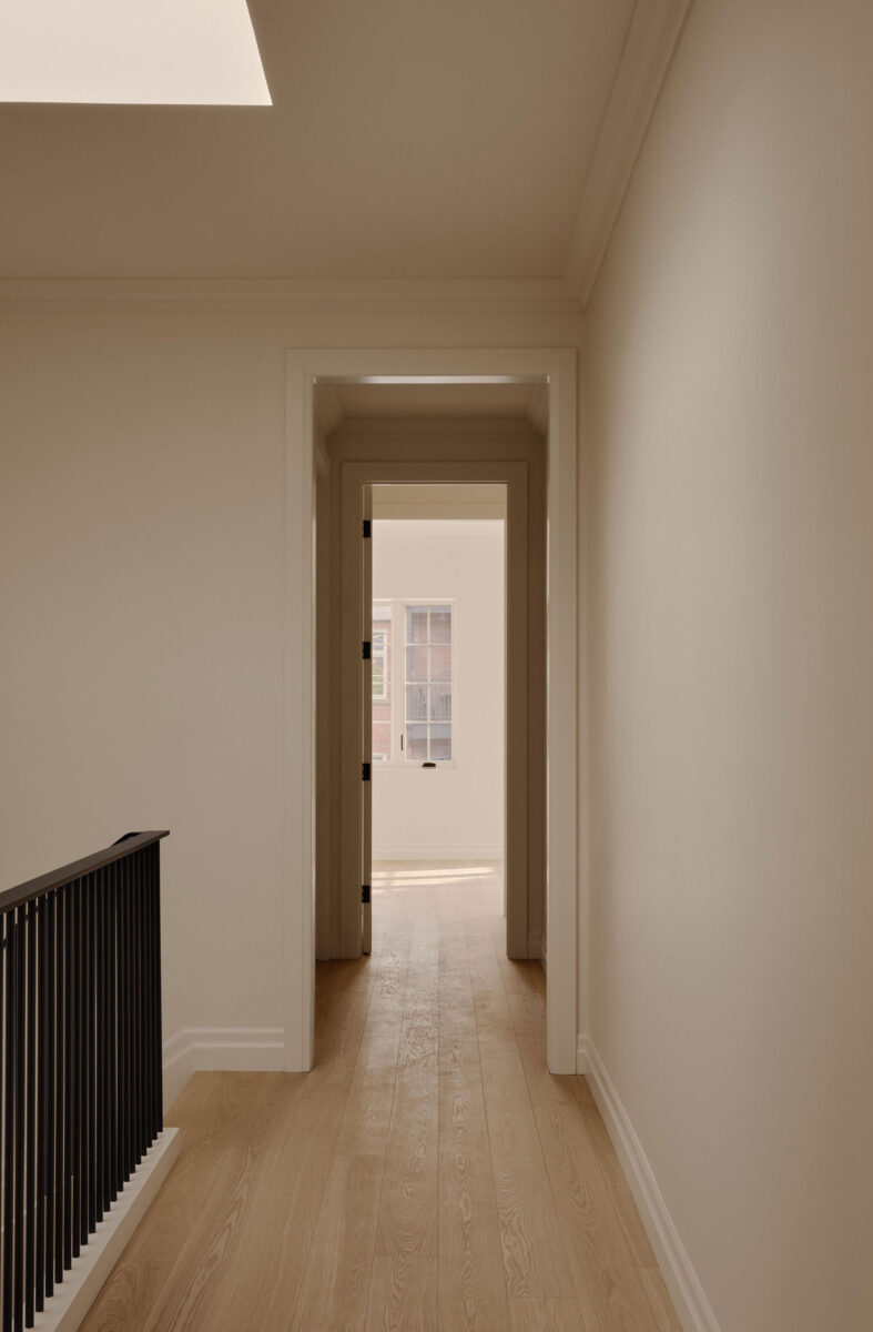Second-floor hallway in Wood Residence with white oak floors, traditional molding and natural light