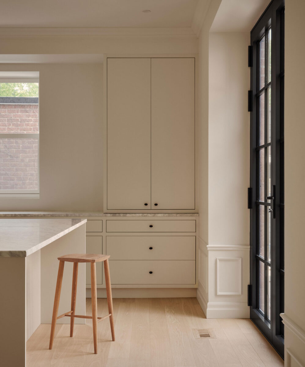 Minimalist Montreal kitchen with white cabinetry, marble countertop and custom built-in storage
