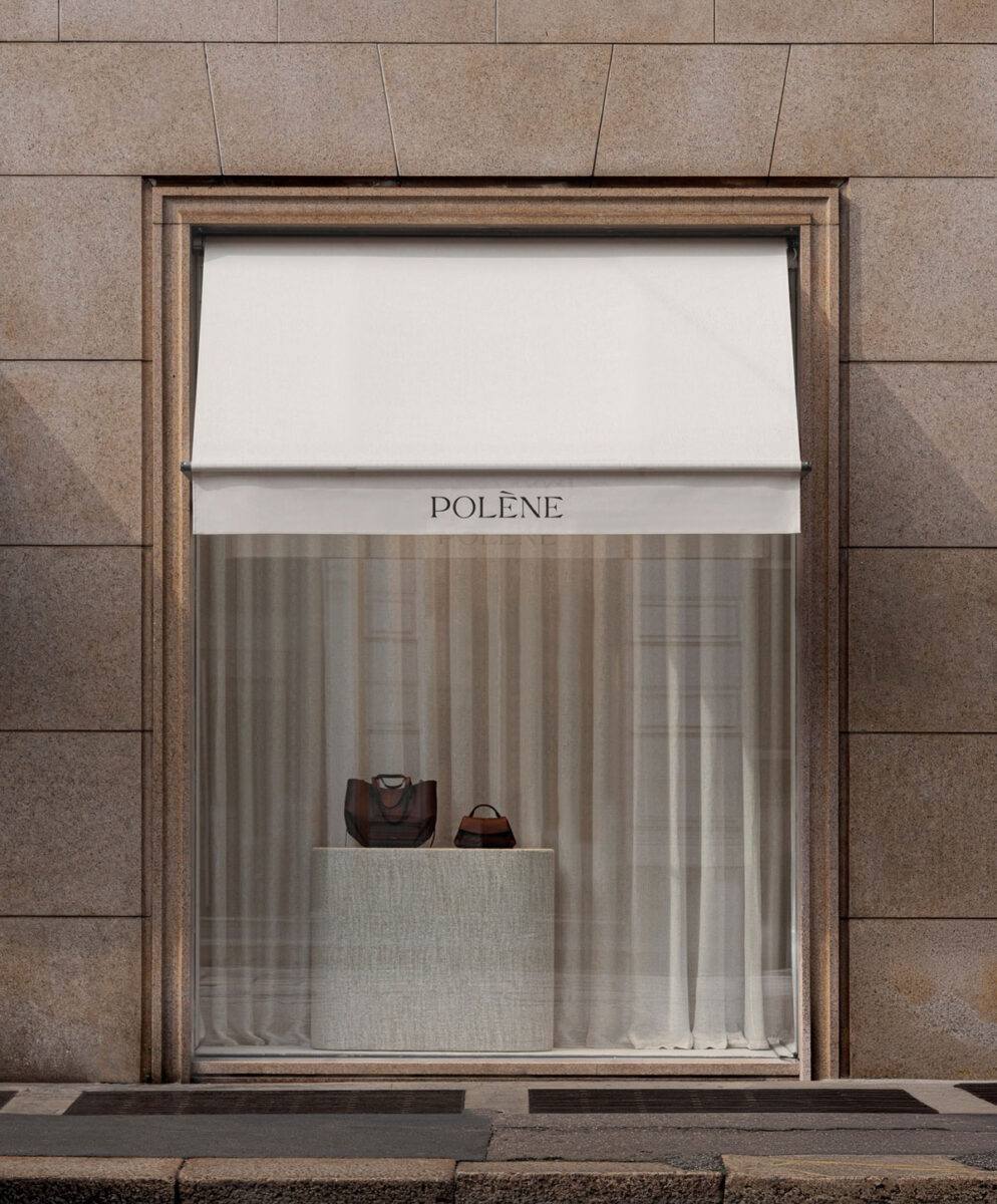 Handbags displayed behind sheer curtains in the storefront window.