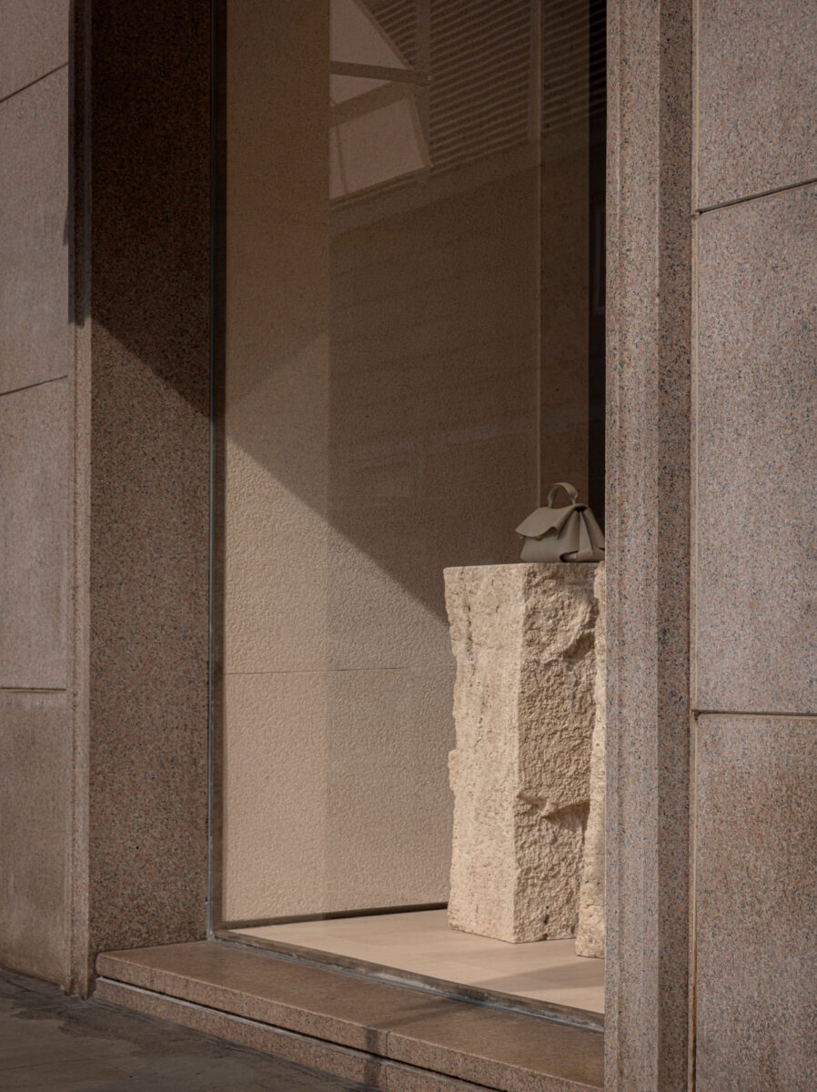 A handbag on a rough stone pedestal inside the store.