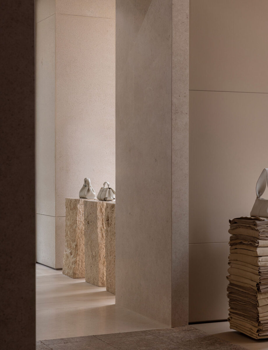 View through the store’s stone rooms to handbags on rough pedestals.