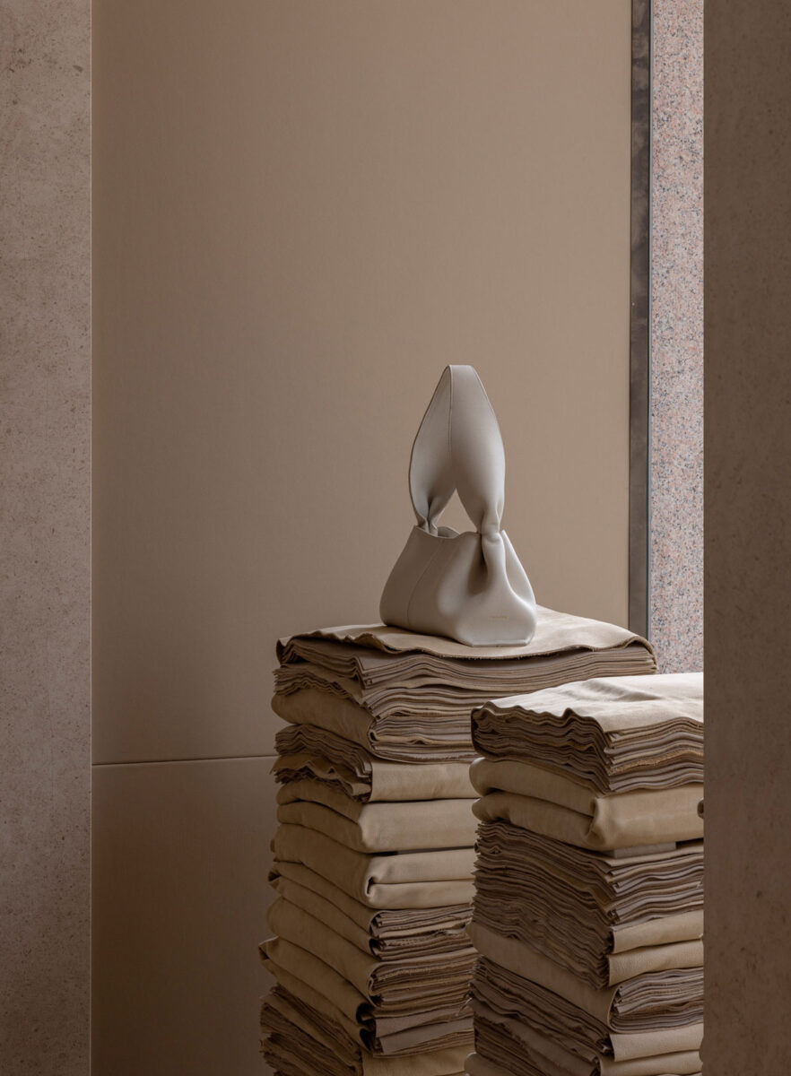 A pale sculptural handbag displayed on stacked suede.
