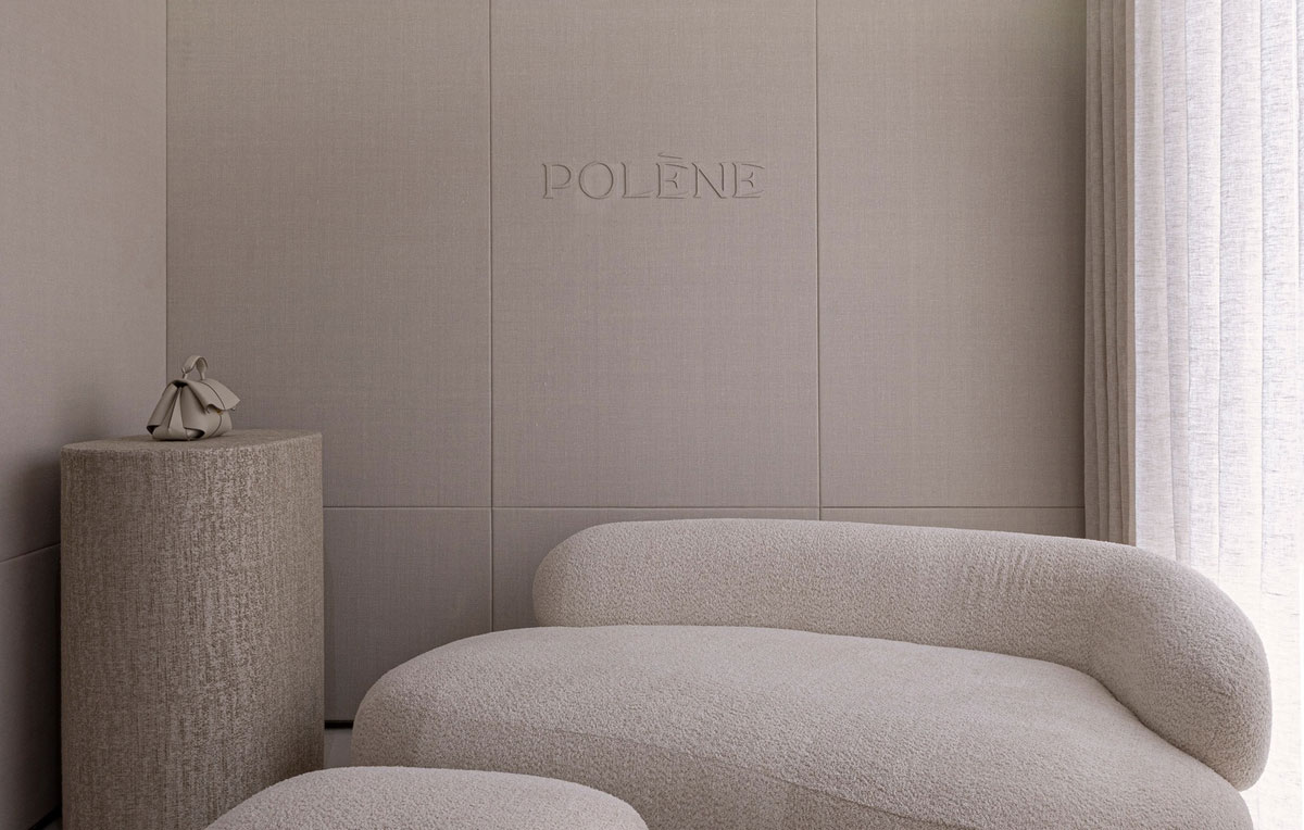 Curved upholstered sofa beside a sheer curtain in Polène’s private room.