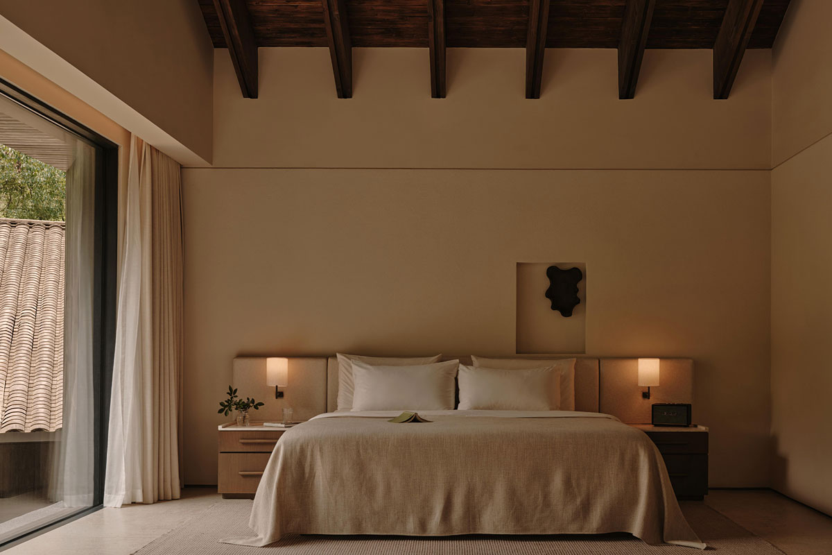 Beige luxury hotel bedroom with a wood-beam ceiling and minimalist interior design