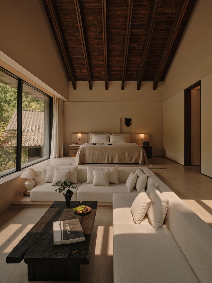 Refined hotel suite with a sunken living room, neutral lounge furniture, warm wood finishes, and custom cabinetry