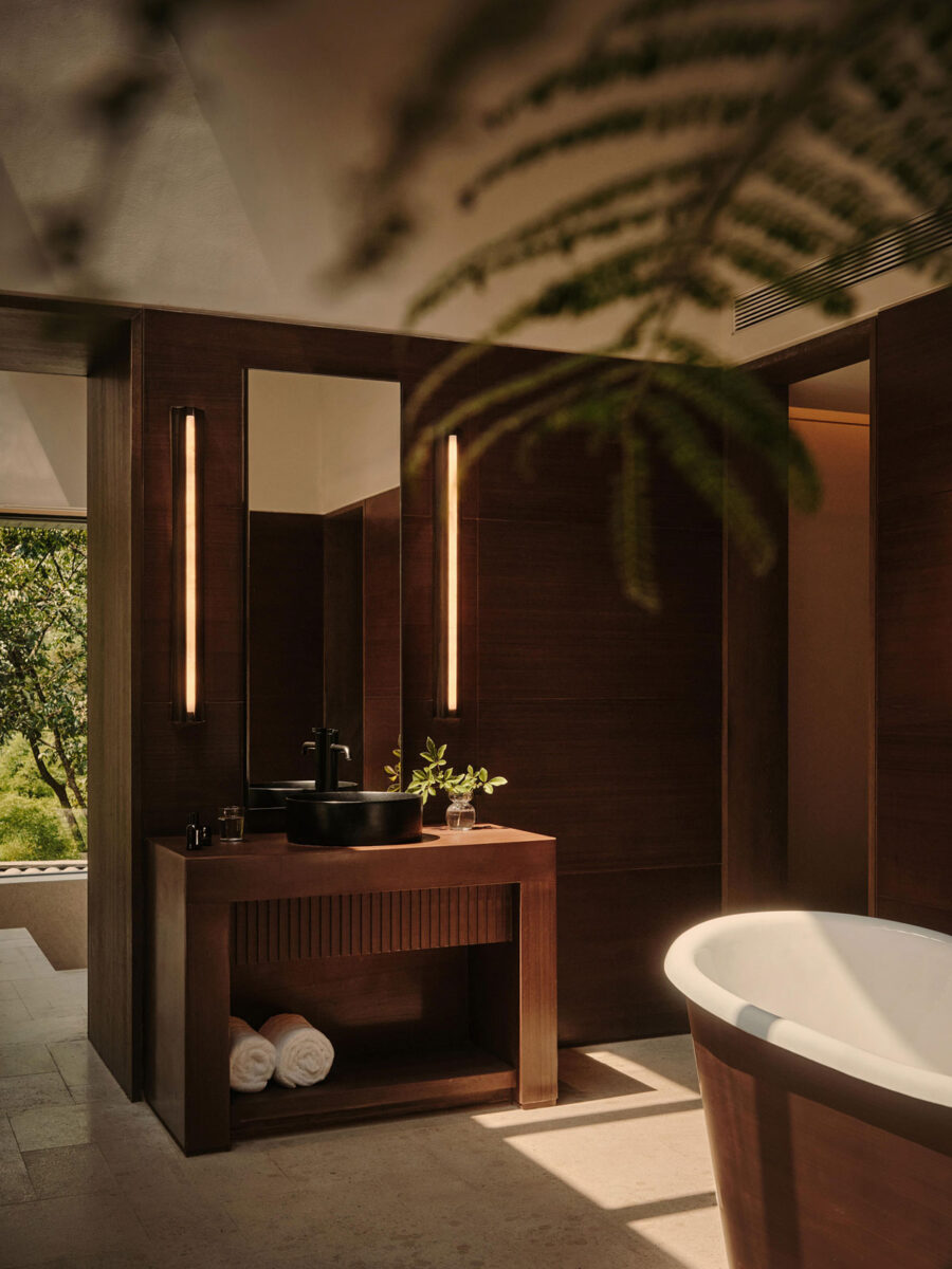Luxury bathroom vanity with dark wood cabinetry, warm stone finishes, and minimalist lighting at ZOLAND·Emei Resort