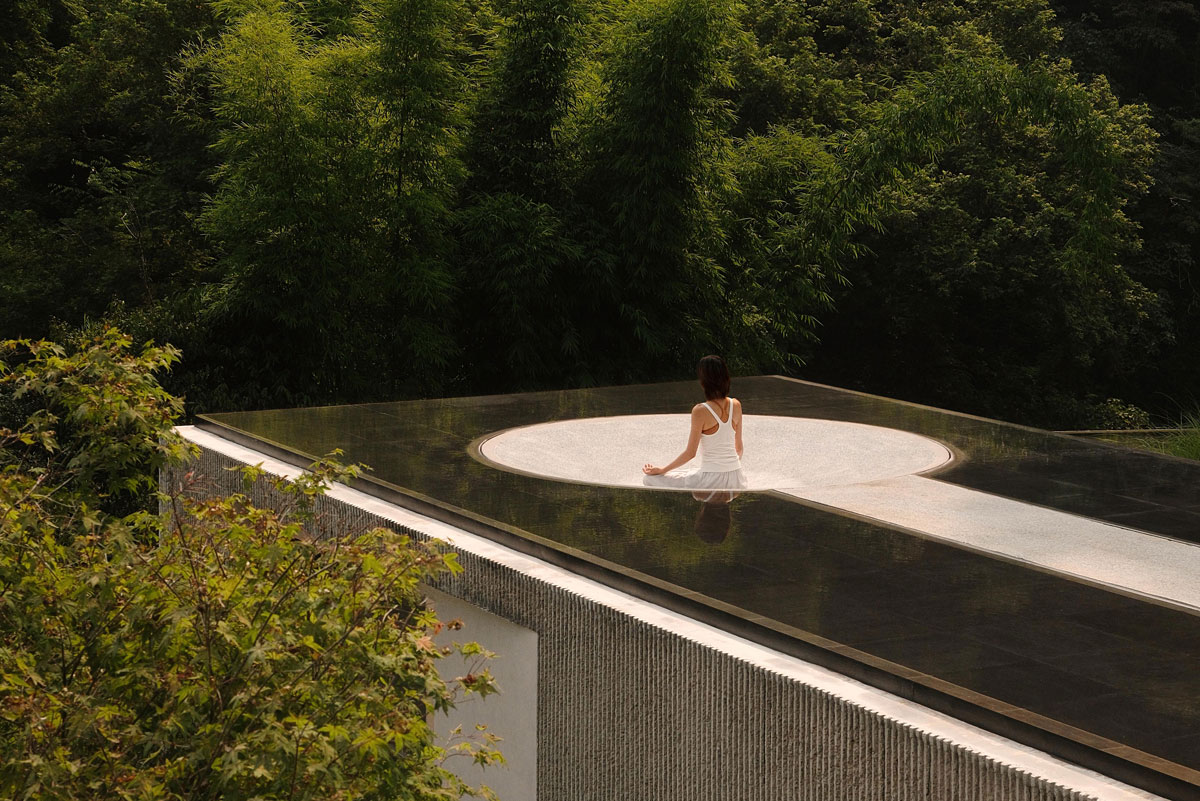 Sculptural rooftop meditation area surrounded by bamboo and dense mountain greenery