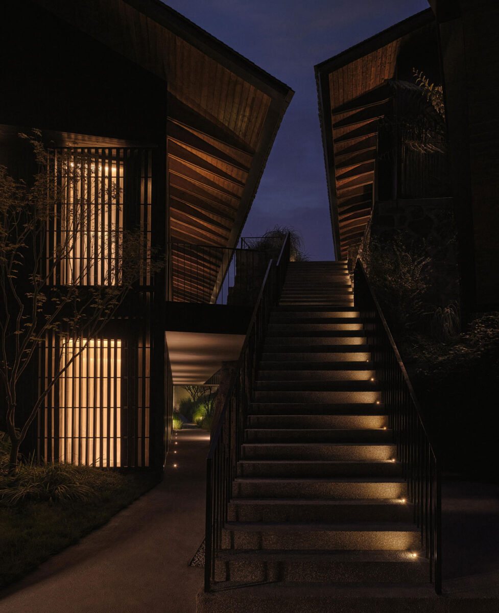 Illuminated stone staircase between dark timber resort buildings at night