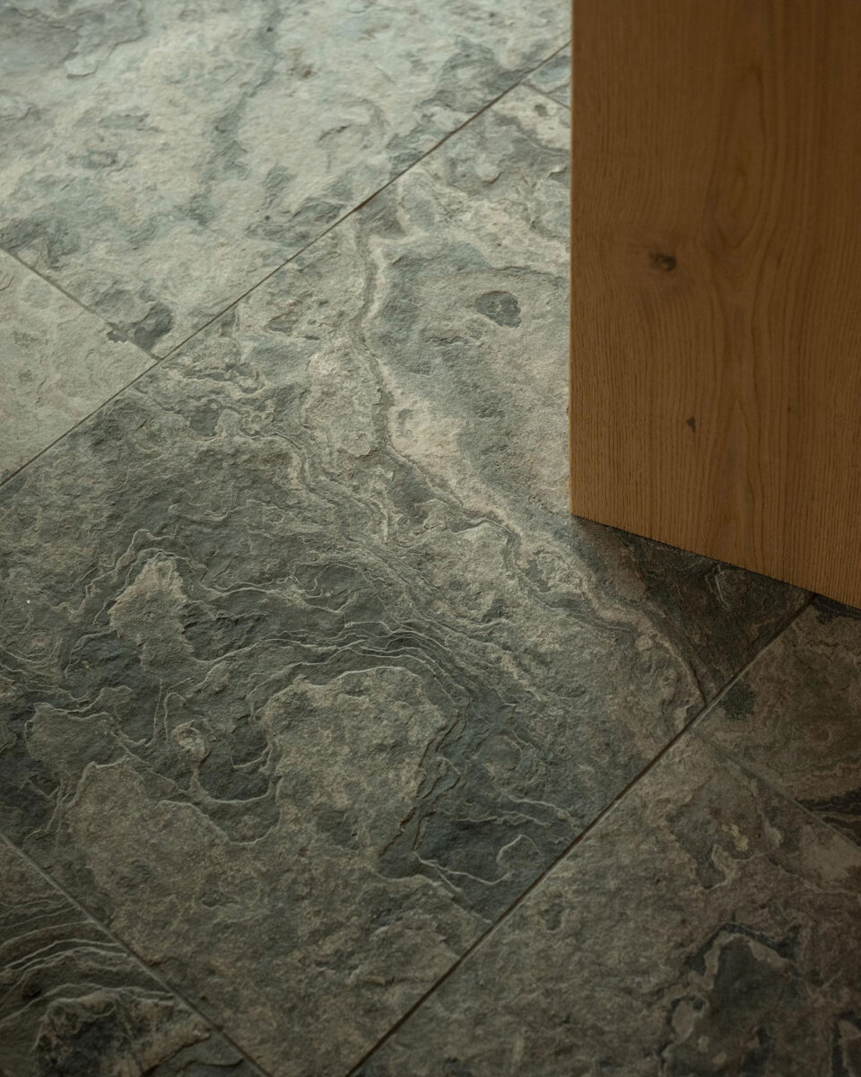 Textured Eramosa stone flooring beside an oak door.